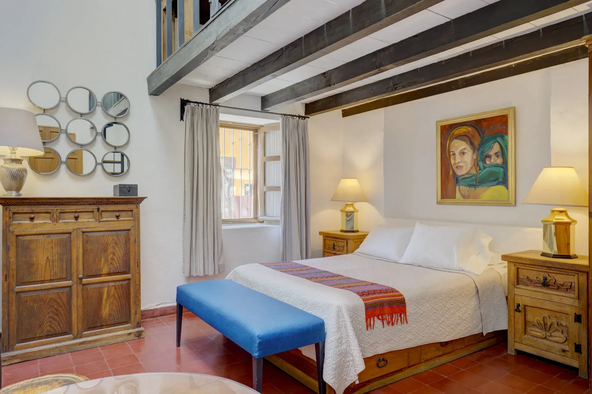 Casa Firenze, bedroom with a white bed, a blue bench, a carved dresser and a loft with beams above, San Miguel de Allende