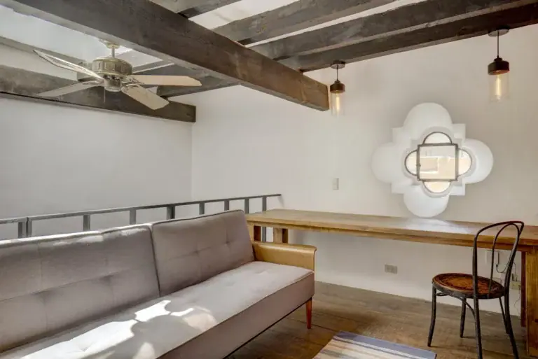Casa Firenze, loft den with a gray sofa, a desk, a ceiling fan and a quatrefoil window, San Miguel de Allende