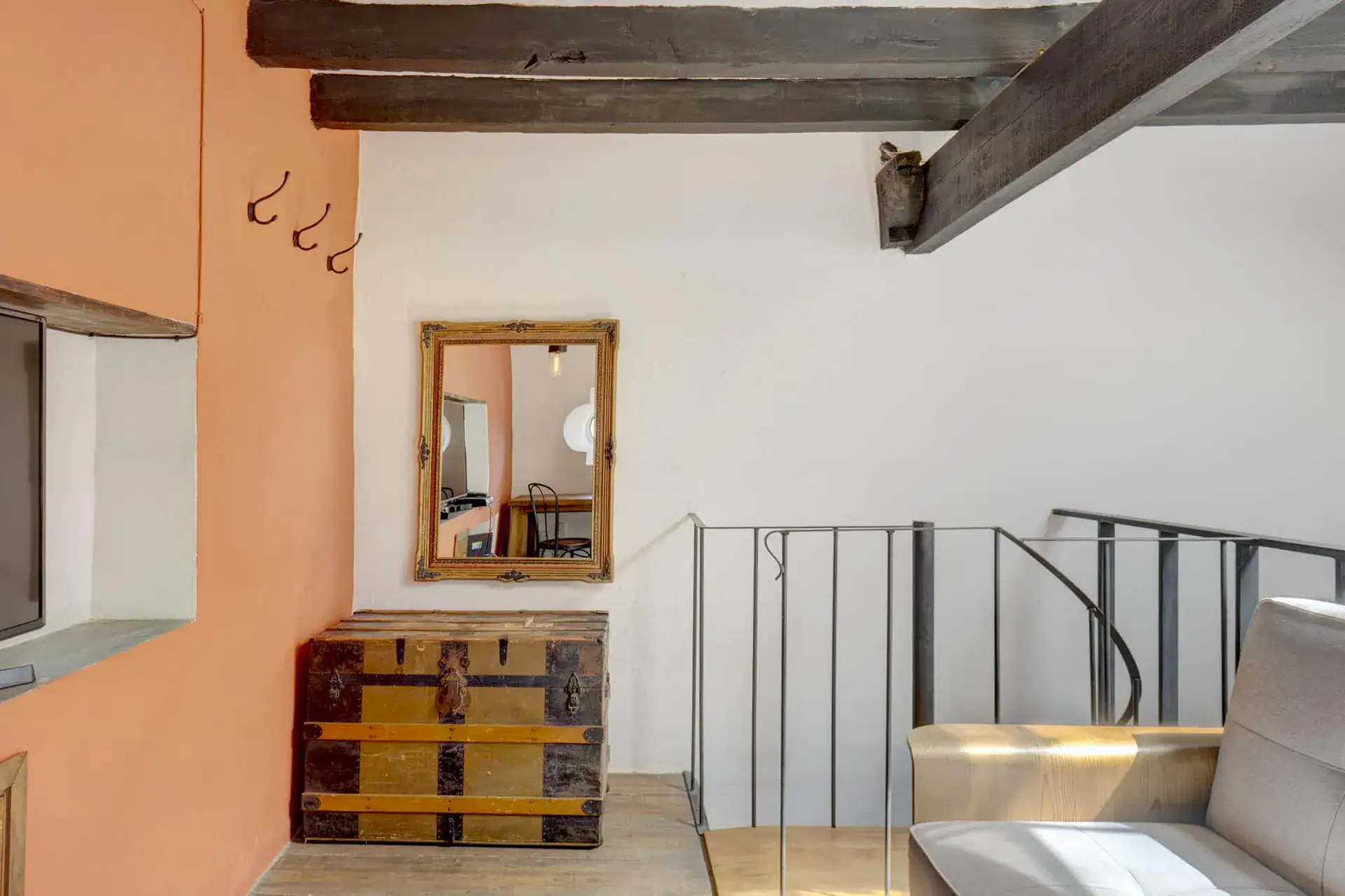 Casa Firenze, loft landing with a wooden trunk, a mirror and a spiral stair railing, San Miguel de Allende
