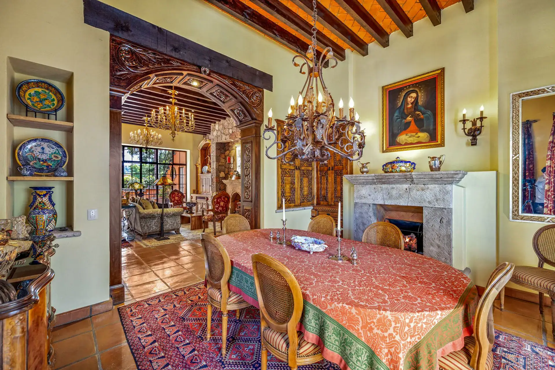Casa Flora, dining room with a coral tablecloth, a stone fireplace and a portrait over the mantel, San Miguel de Allende