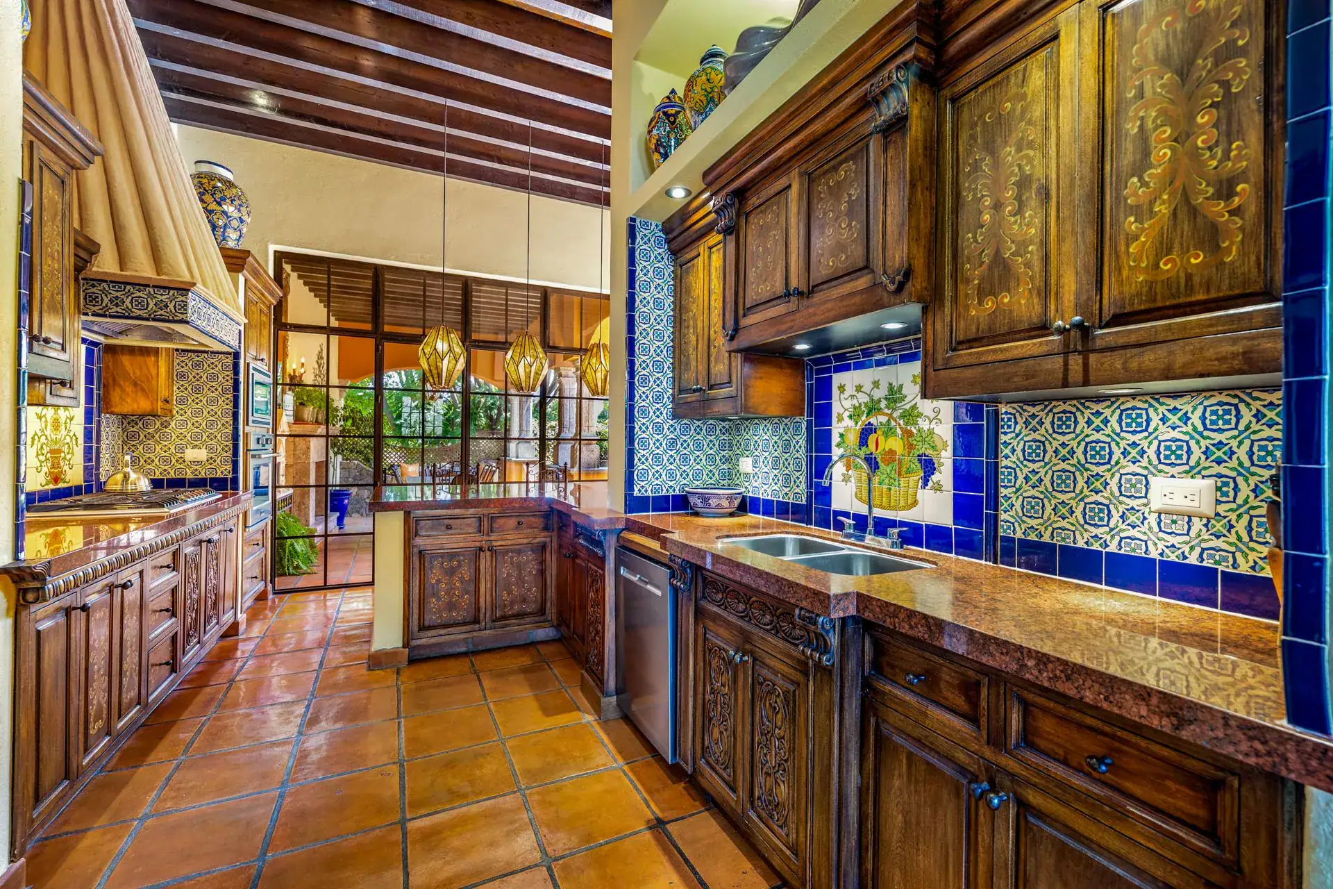 Casa Flora, kitchen with carved wood cabinets, blue and yellow Talavera tile and a copper-topped counter, San Miguel de Allende
