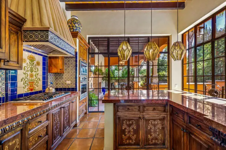 Casa Flora, kitchen with a tiled range hood, a copper-topped island and pendant lights beside glass doors, San Miguel de Allende