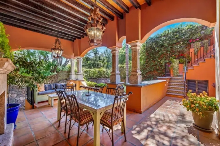 Casa Flora, covered loggia with a dining table, stone arches and a staircase to the upper level, San Miguel de Allende
