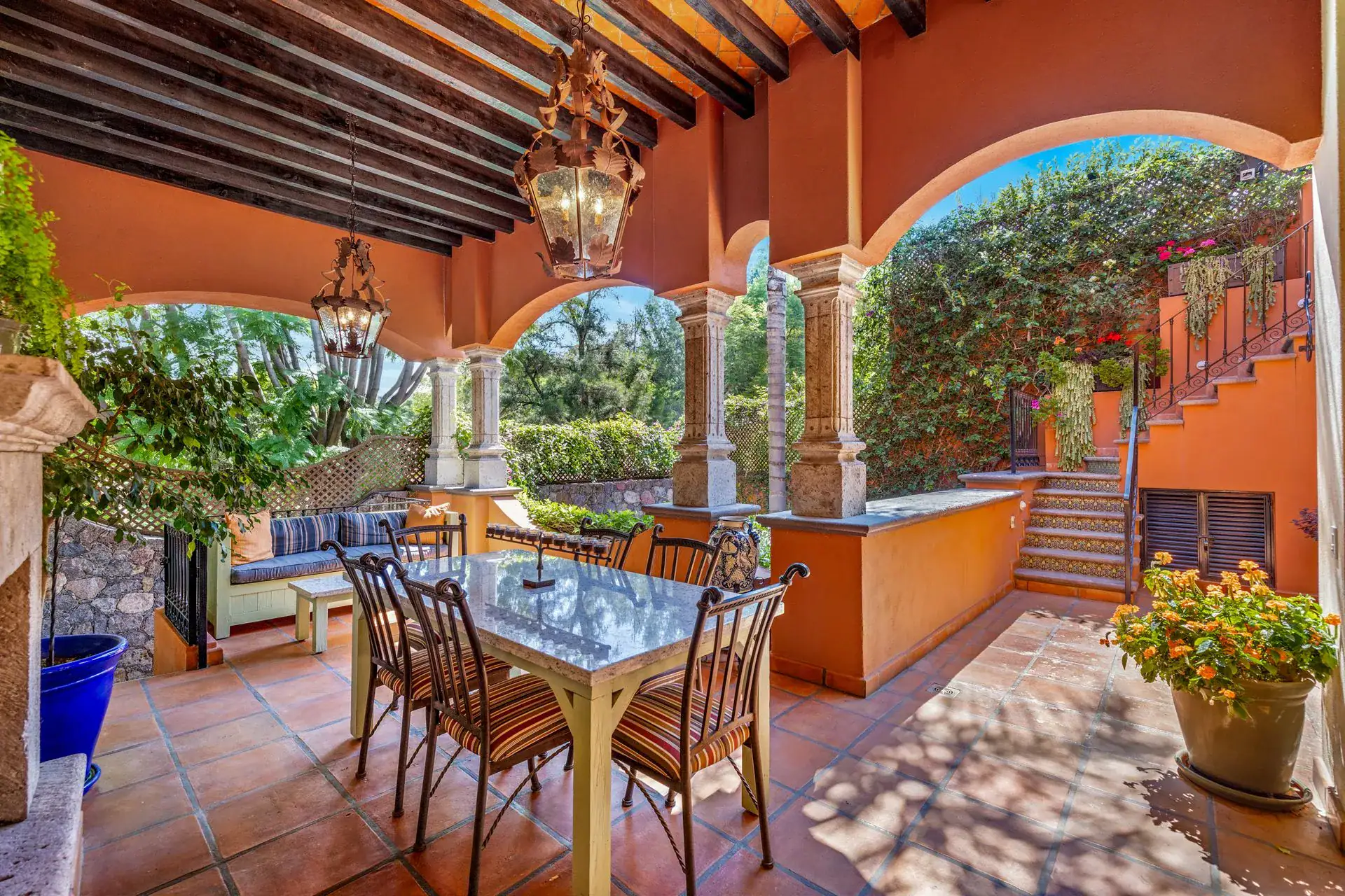 Casa Flora, covered loggia with a dining table, stone arches and a staircase to the upper level, San Miguel de Allende