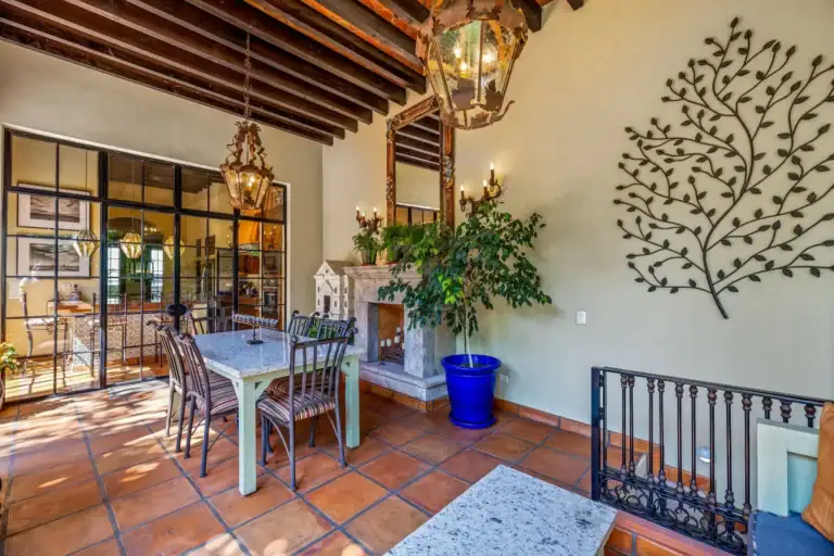 Casa Flora, dining nook with a fireplace, a tree wall sculpture and a steel-framed glass wall, San Miguel de Allende