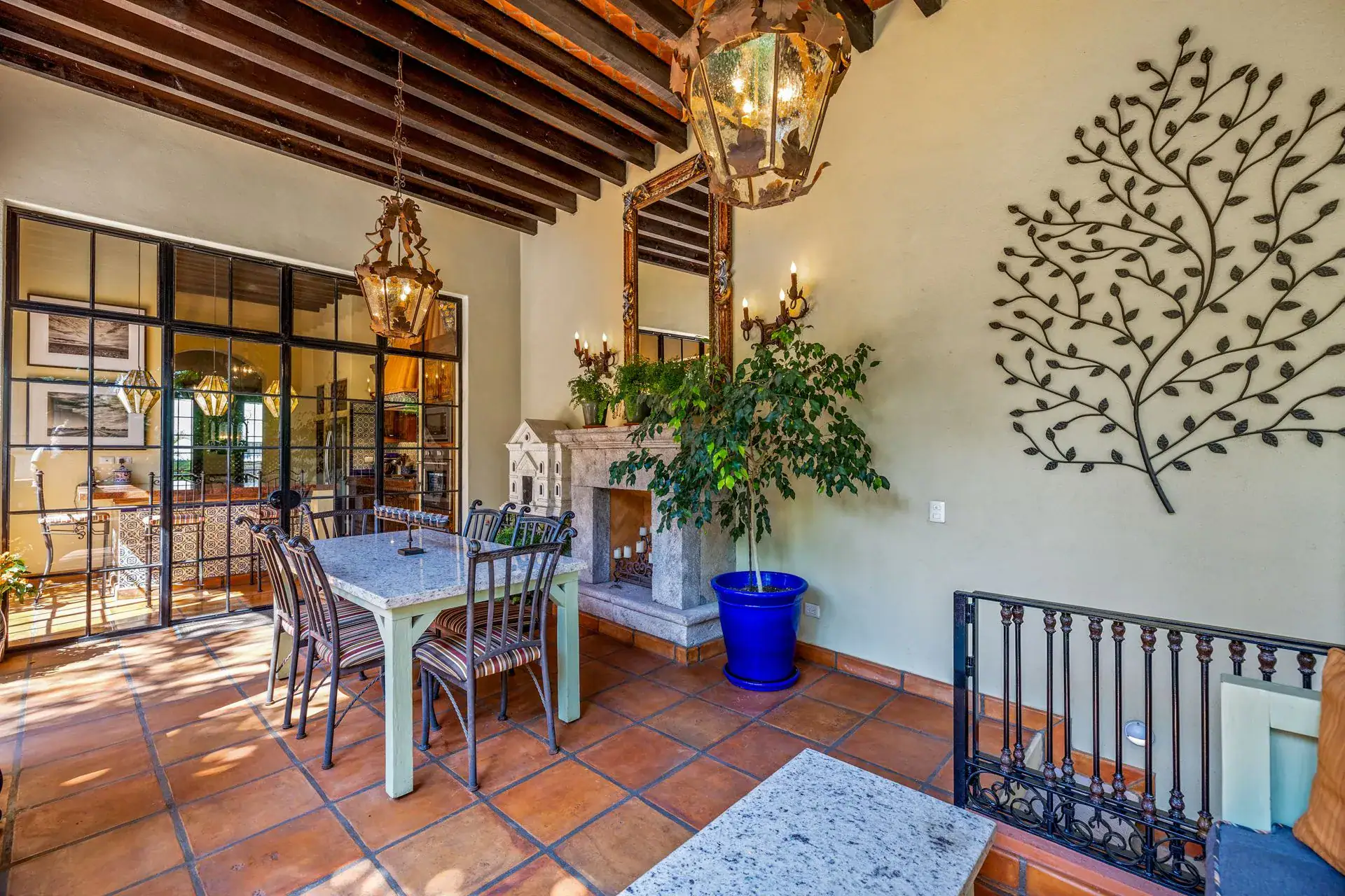 Casa Flora, dining nook with a fireplace, a tree wall sculpture and a steel-framed glass wall, San Miguel de Allende