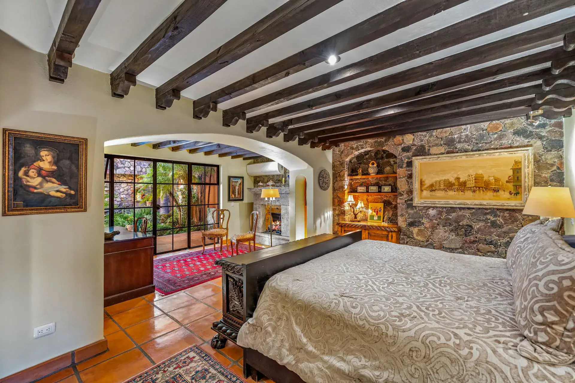 Casa Flora, bedroom with a carved wood bed, a stone wall niche and a beamed ceiling, San Miguel de Allende