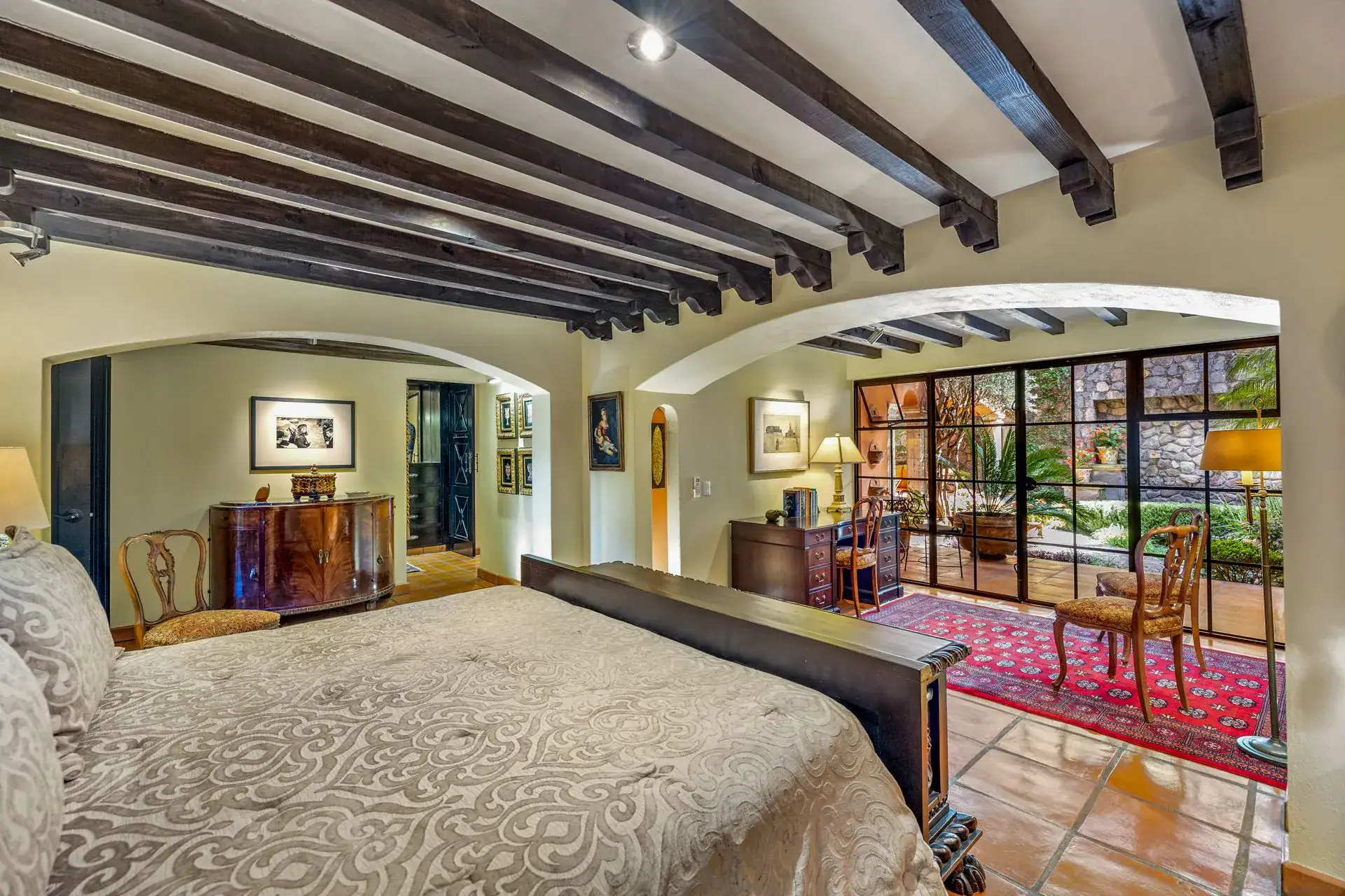 Casa Flora, bedroom with a carved wood bed, a writing desk and glass doors to the courtyard, San Miguel de Allende