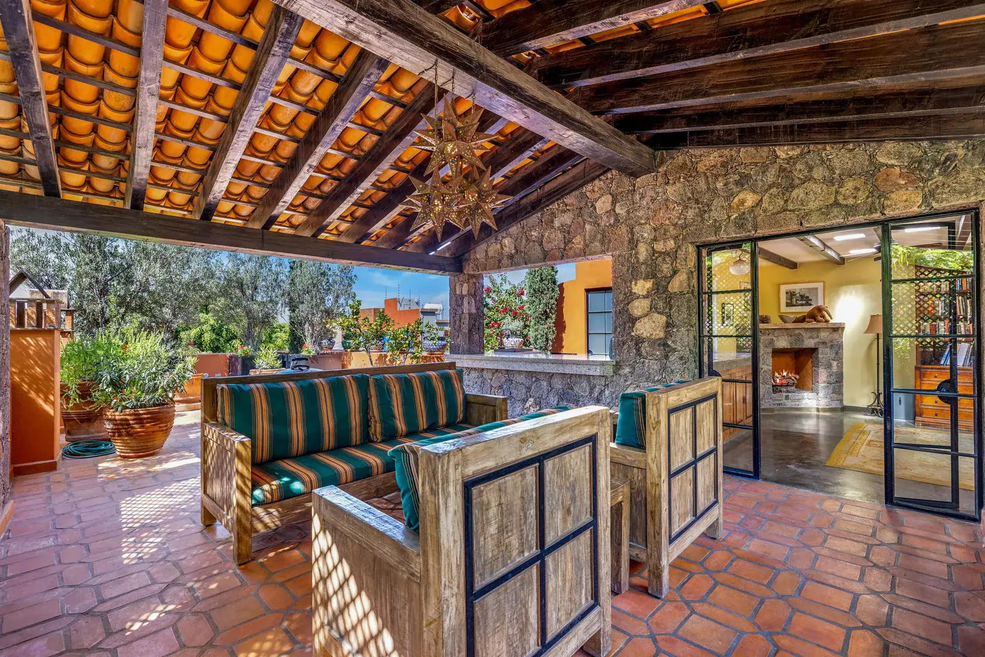 Casa Flora, covered terrace with striped sofas, a tile ceiling and a view into a room with a fireplace, San Miguel de Allende
