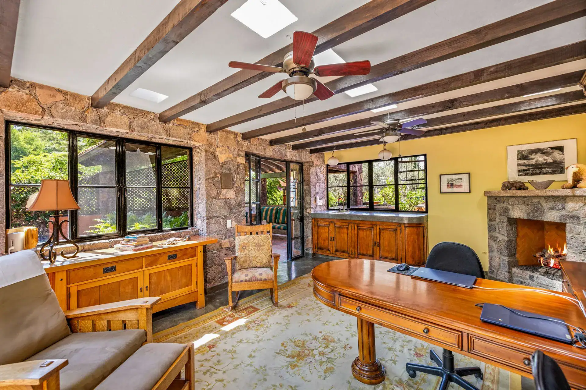 Casa Flora, study with a large wood desk, a sofa and a stone fireplace, San Miguel de Allende