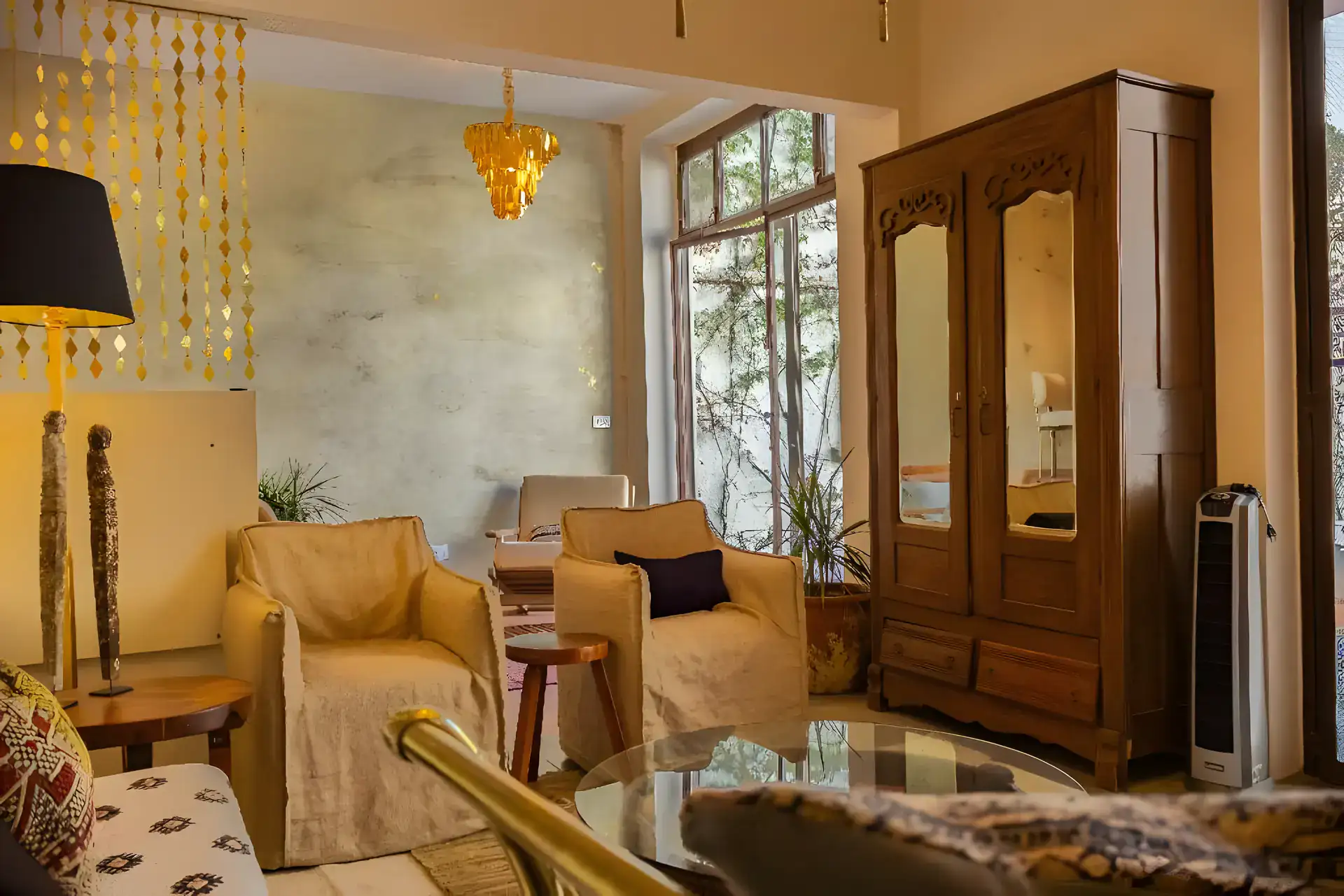 Casa Garza, suite living room with slipcovered armchairs, a carved wood armoire with mirrors and a brass bead curtain, San Miguel de Allende