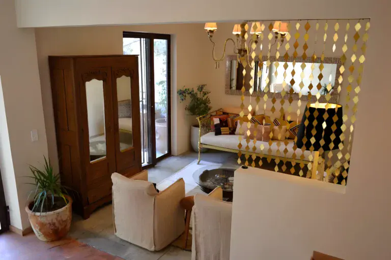 Casa Garza, living area with a carved wood armoire, a brass diamond screen and a linen sofa, San Miguel de Allende
