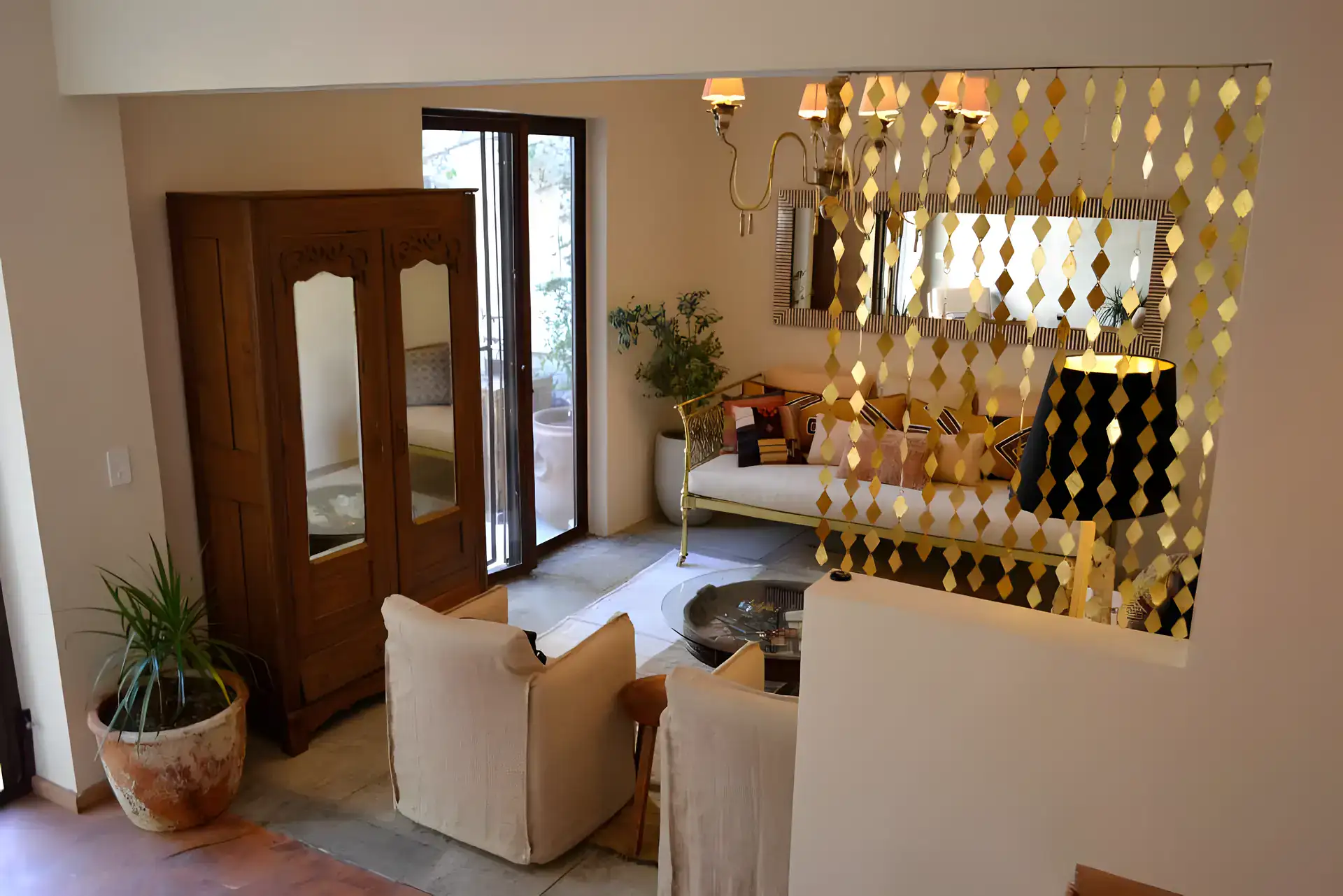 Casa Garza, living area with a carved wood armoire, a brass diamond screen and a linen sofa, San Miguel de Allende