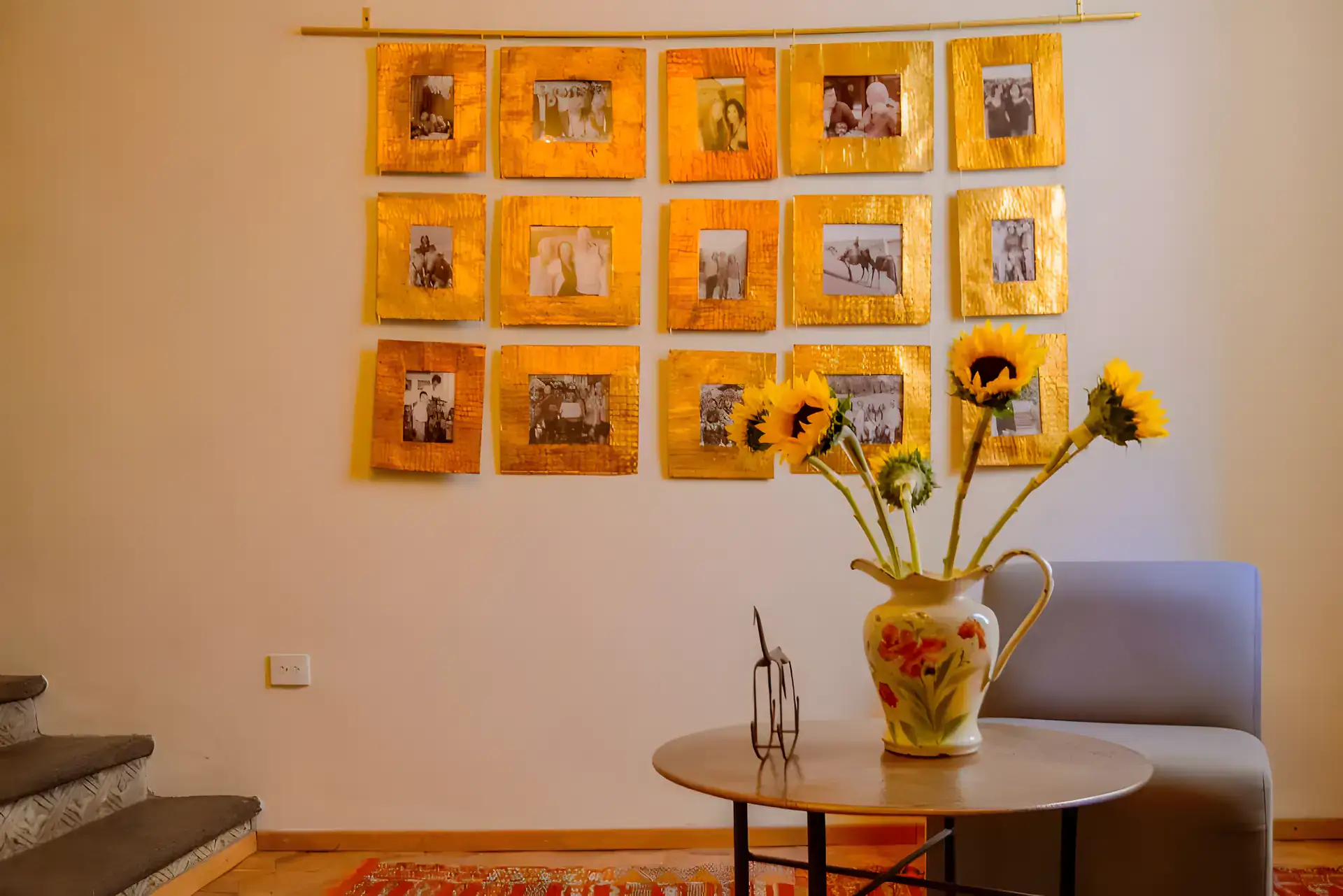 Casa Garza, wall of gold-framed family photographs with a vase of sunflowers on a round table, San Miguel de Allende