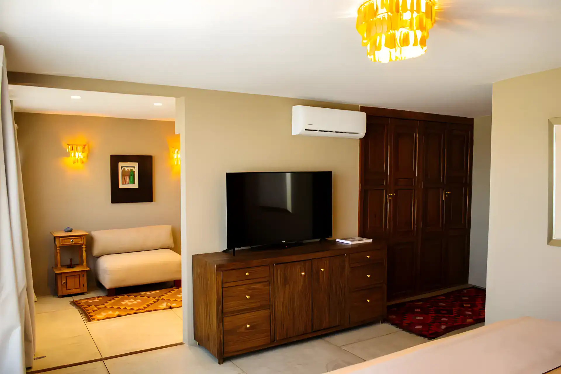 Casa Garza, suite with a wall-mounted television on a wood dresser, a wardrobe and a gold pendant light, San Miguel de Allende