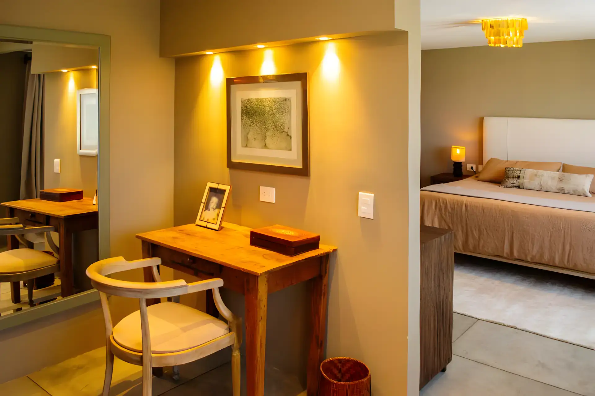 Casa Garza, desk with a wood chair and a mirror, a lit picture and a bed behind, San Miguel de Allende