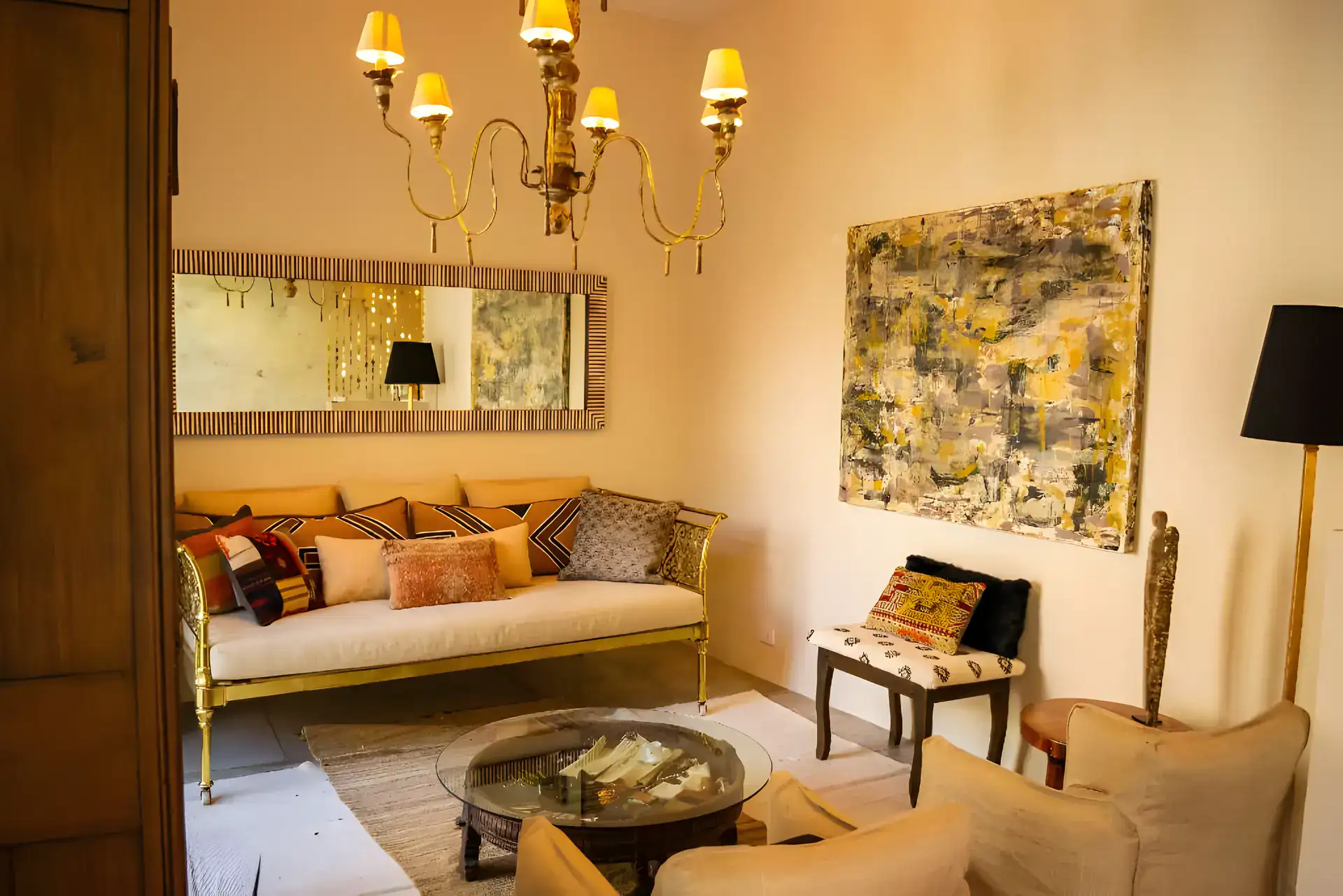 Casa Garza, sitting room with a brass sofa, a round table, a chandelier and an abstract painting, San Miguel de Allende