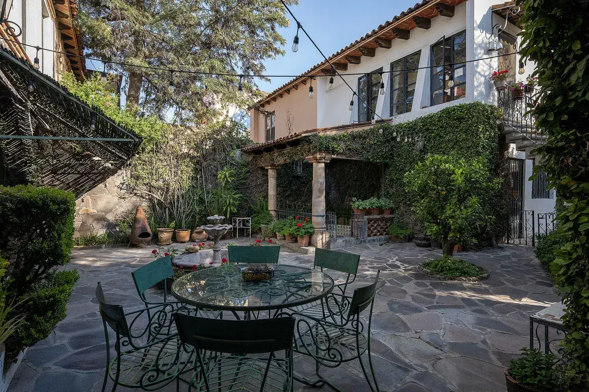 Casa Gracia, courtyard with a glass table and chairs below an ivy-covered house, San Miguel de Allende