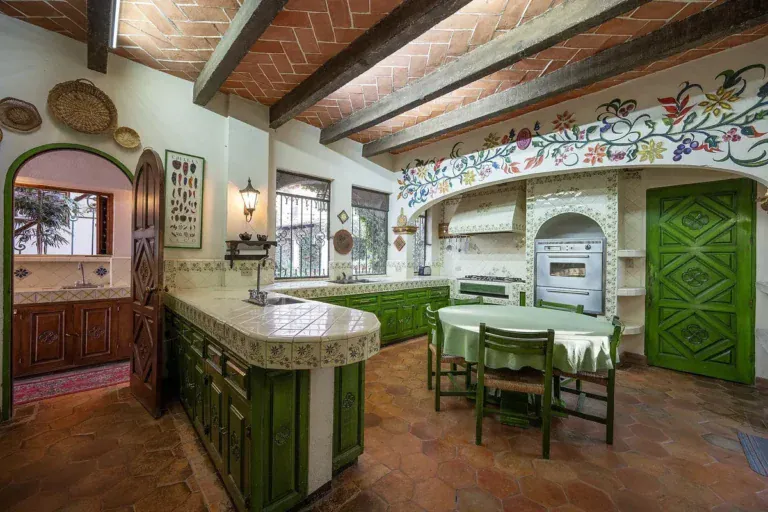 Casa Gracia, kitchen with green cabinets, a tiled counter and a painted tile frieze, San Miguel de Allende