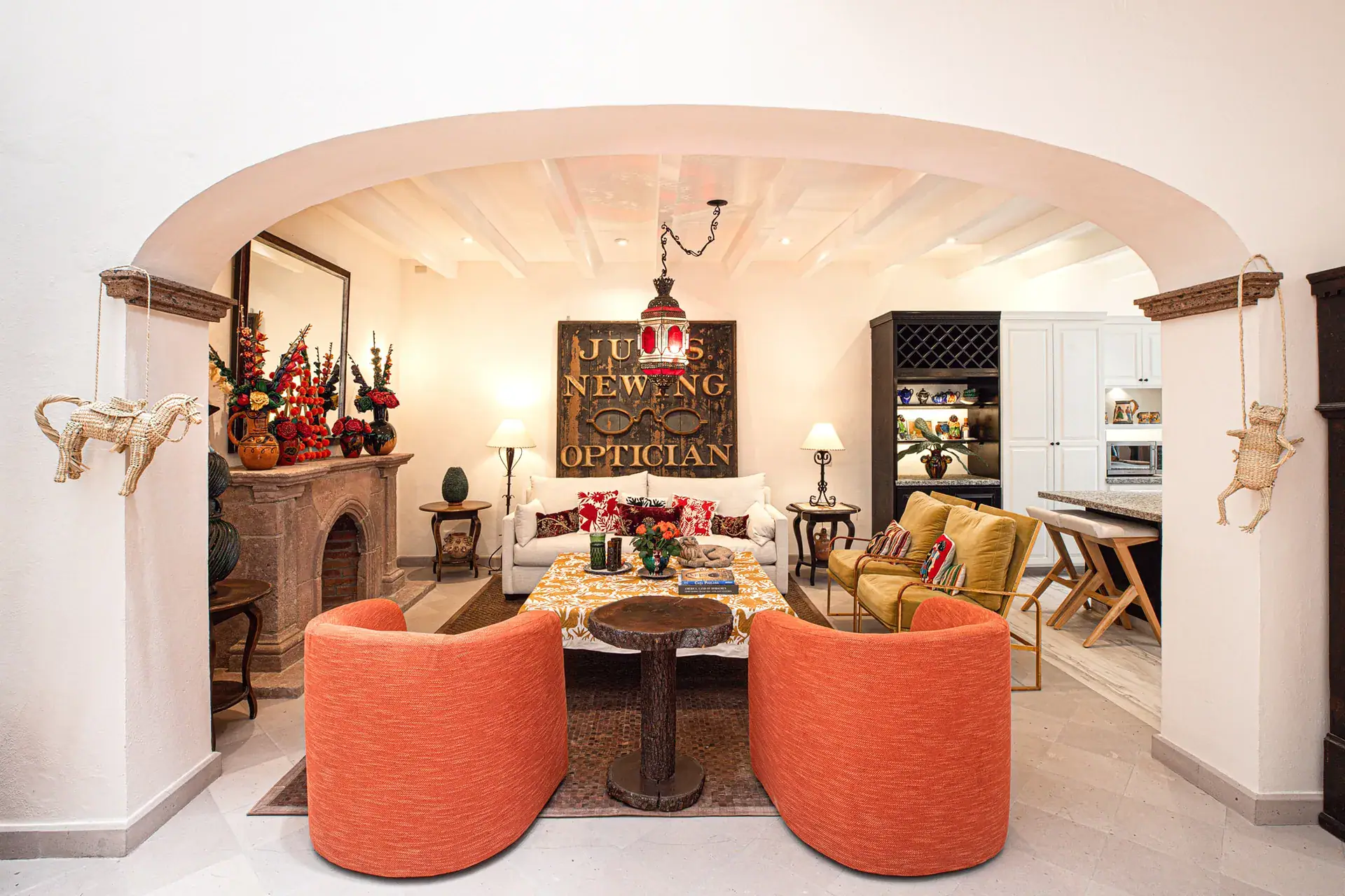 Casa Grillo, living room with orange chairs, a stone fireplace and a patterned runner, San Miguel de Allende