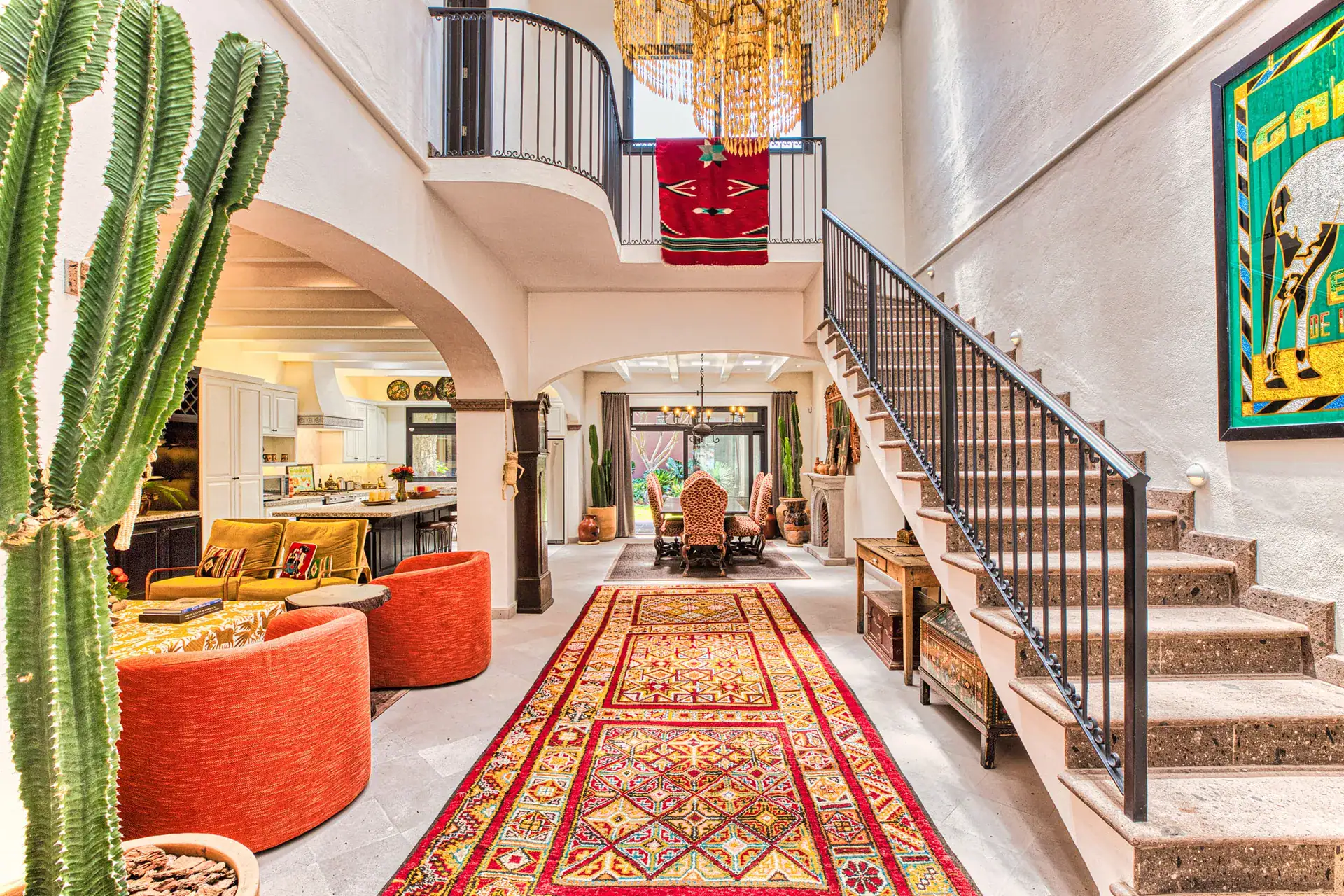 Casa Grillo, living area and staircase with cactus in the foreground and a chandelier, San Miguel de Allende