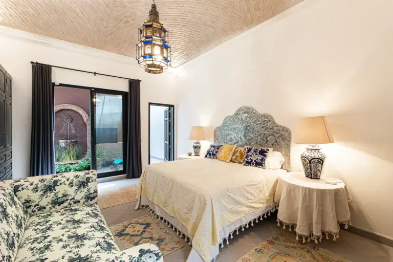 Casa Grillo, bedroom with a carved headboard, floral chair and a brick vaulted ceiling, San Miguel de Allende