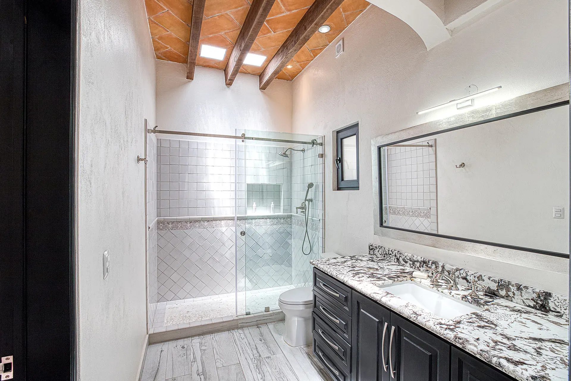 Casa Grillo, bathroom with a glass shower and a dark double vanity, San Miguel de Allende