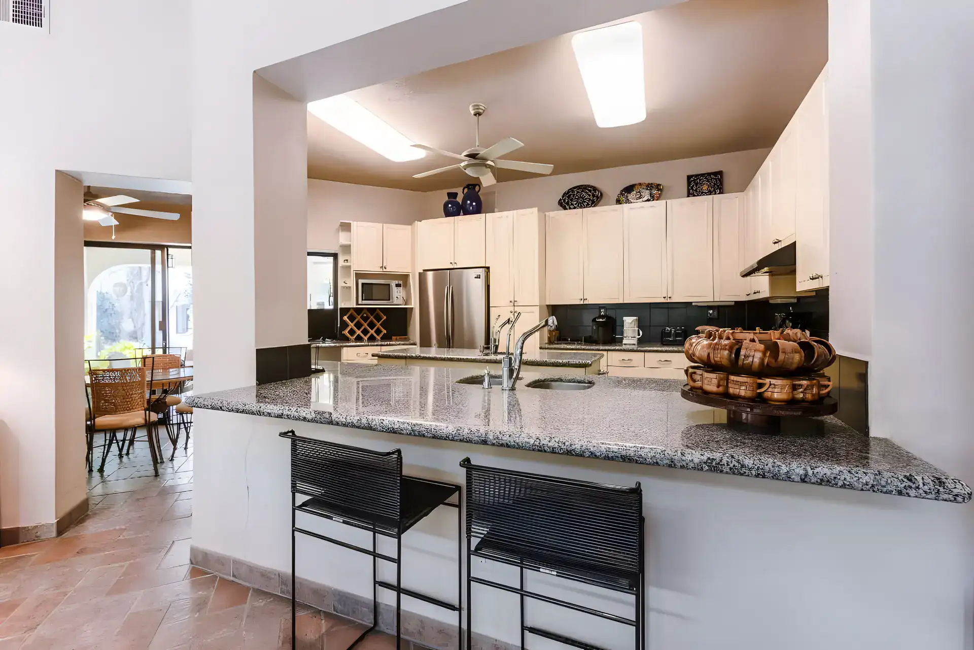 Casa Guadiana, kitchen with white cabinets, a granite counter with black stools and a stainless refrigerator, San Miguel de Allende