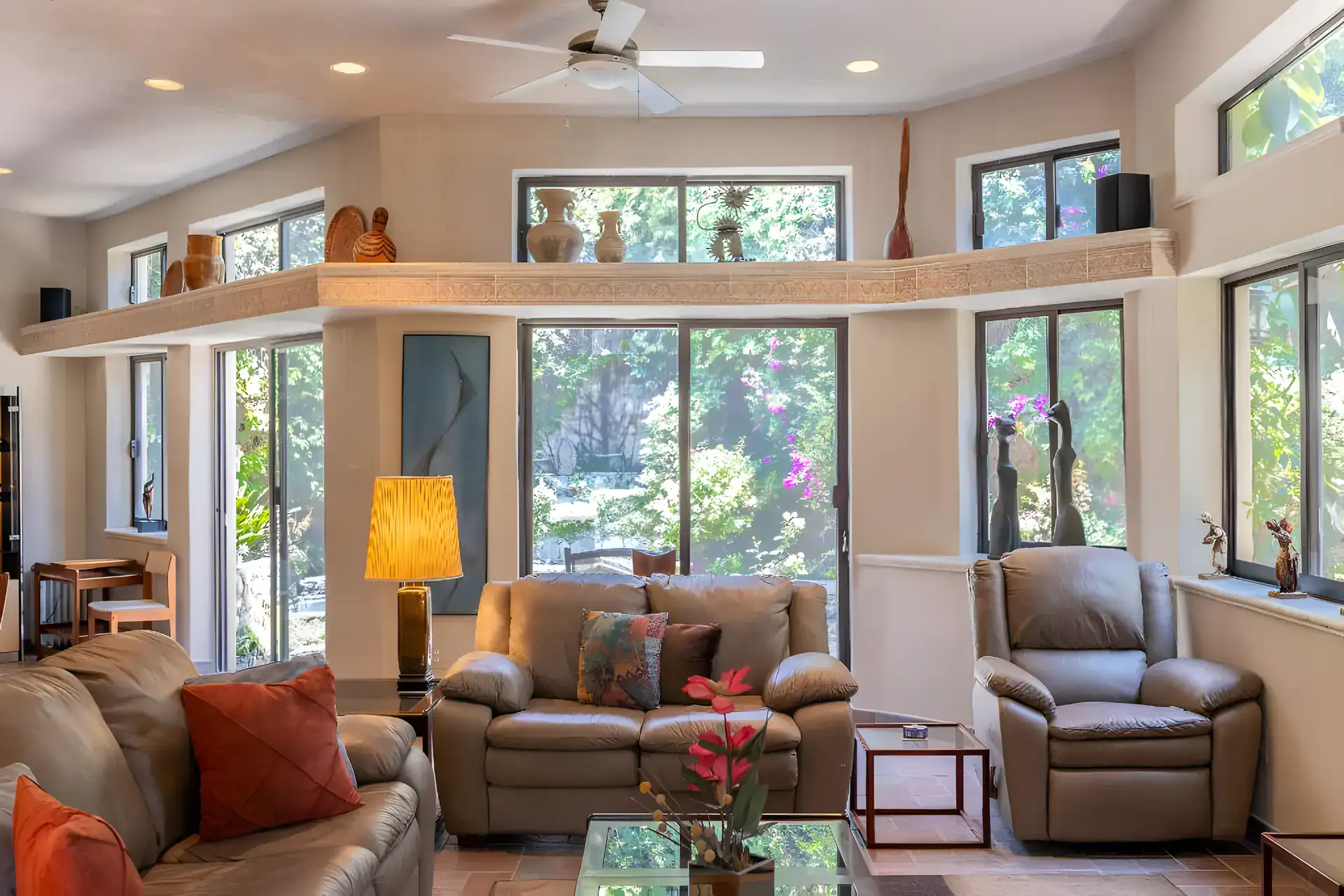 Casa Guadiana, living room with leather sofas and recliners surrounded by tall garden windows, San Miguel de Allende