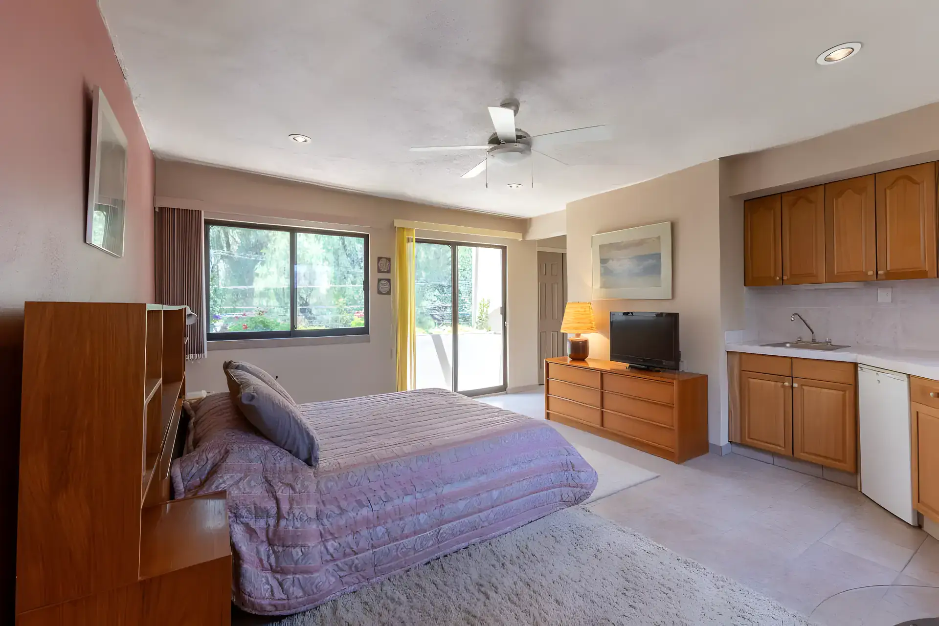 Casa Guadiana, guest bedroom with a purple quilt, kitchenette cabinets and a sliding glass door, San Miguel de Allende