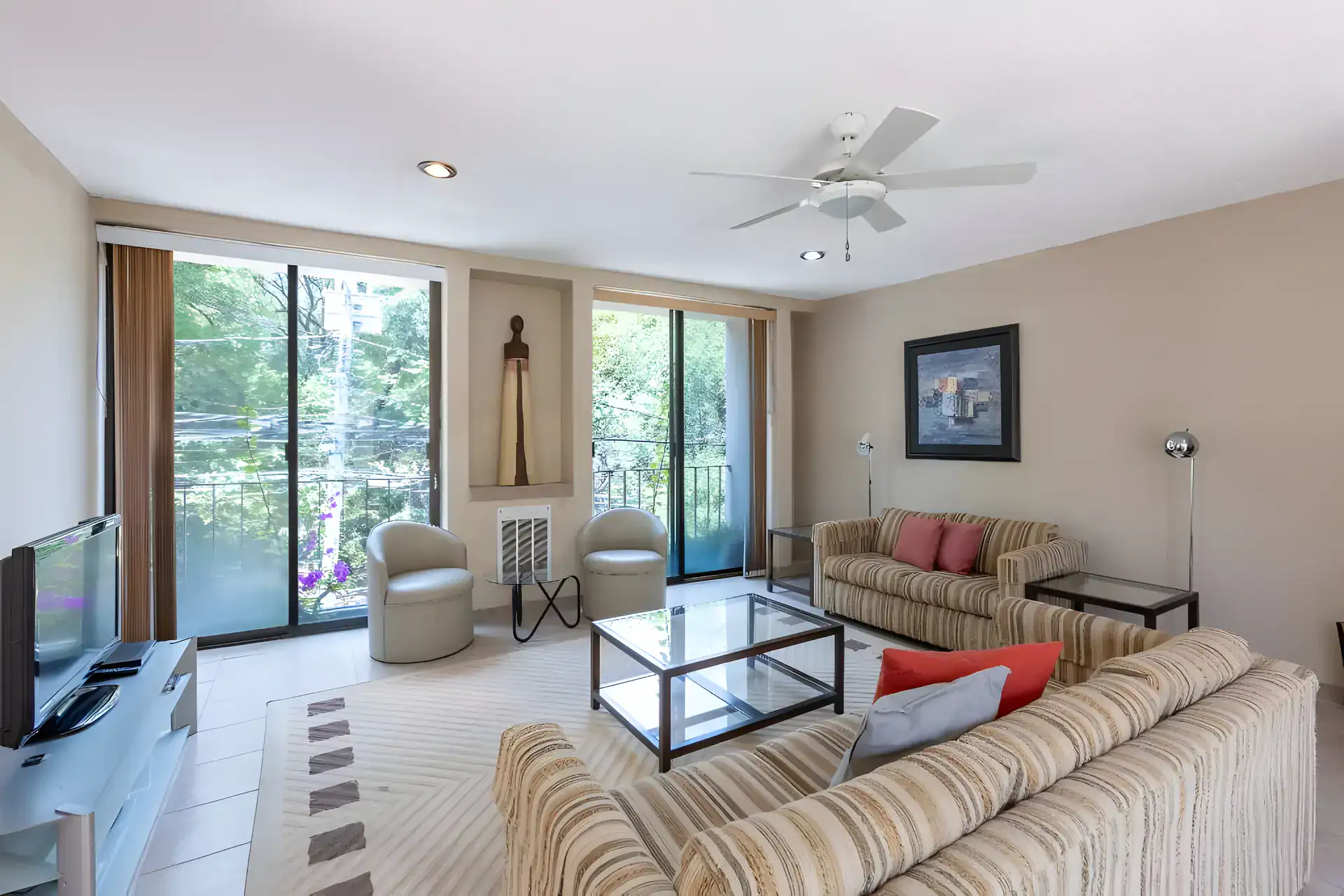 Casa Guadiana, upstairs living room with striped sofas, a glass table and a balcony view, San Miguel de Allende