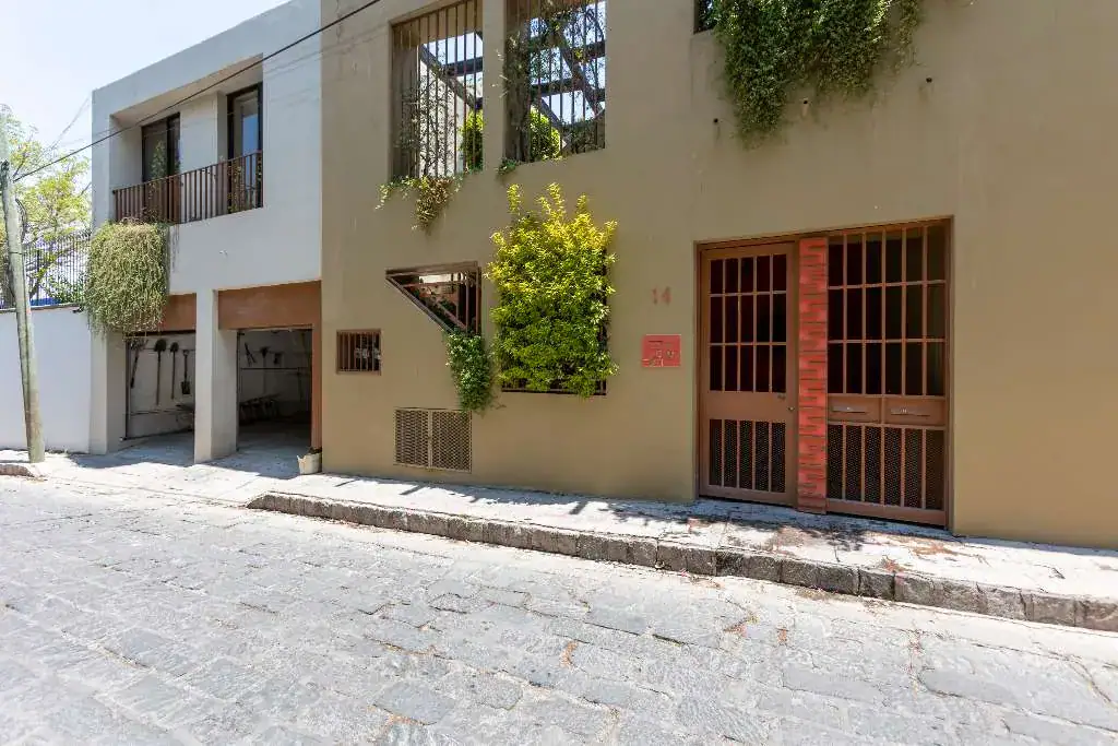 Casa Guadiana, street facade of the house with a barred wooden gate and a green wall of plants, San Miguel de Allende