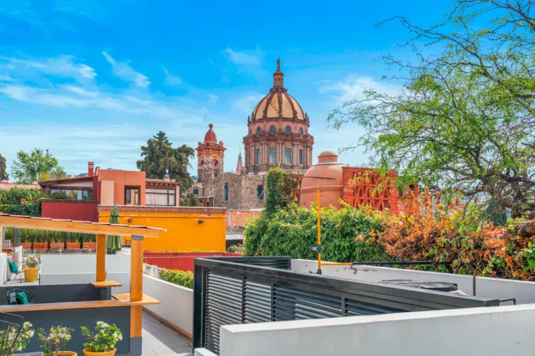 Casa Hidalgo, view over a roof and a modern wall toward the Parroquia dome and the colorful neighborhood rooftops, San Miguel de Allende