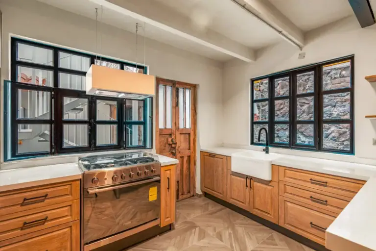 Casa Hidalgo, kitchen with a stainless gas range, a farmhouse sink, wood cabinets and black-framed windows, San Miguel de Allende
