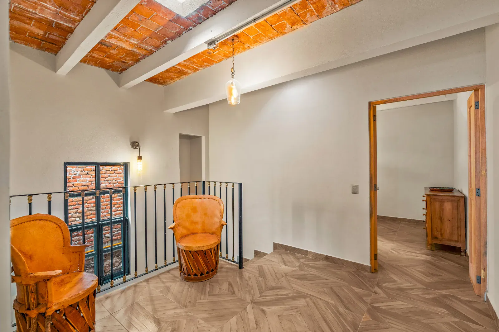 Casa Hidalgo, landing with a black railing, two equipale chairs and a doorway to a bedroom under a vaulted ceiling, San Miguel de Allende
