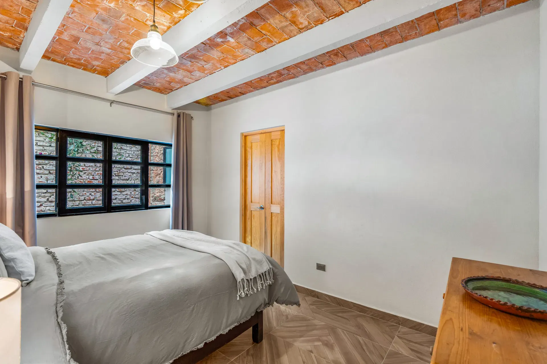 Casa Hidalgo, bedroom with a twin bed with gray bedding, a wood chest and a brick vaulted ceiling, San Miguel de Allende