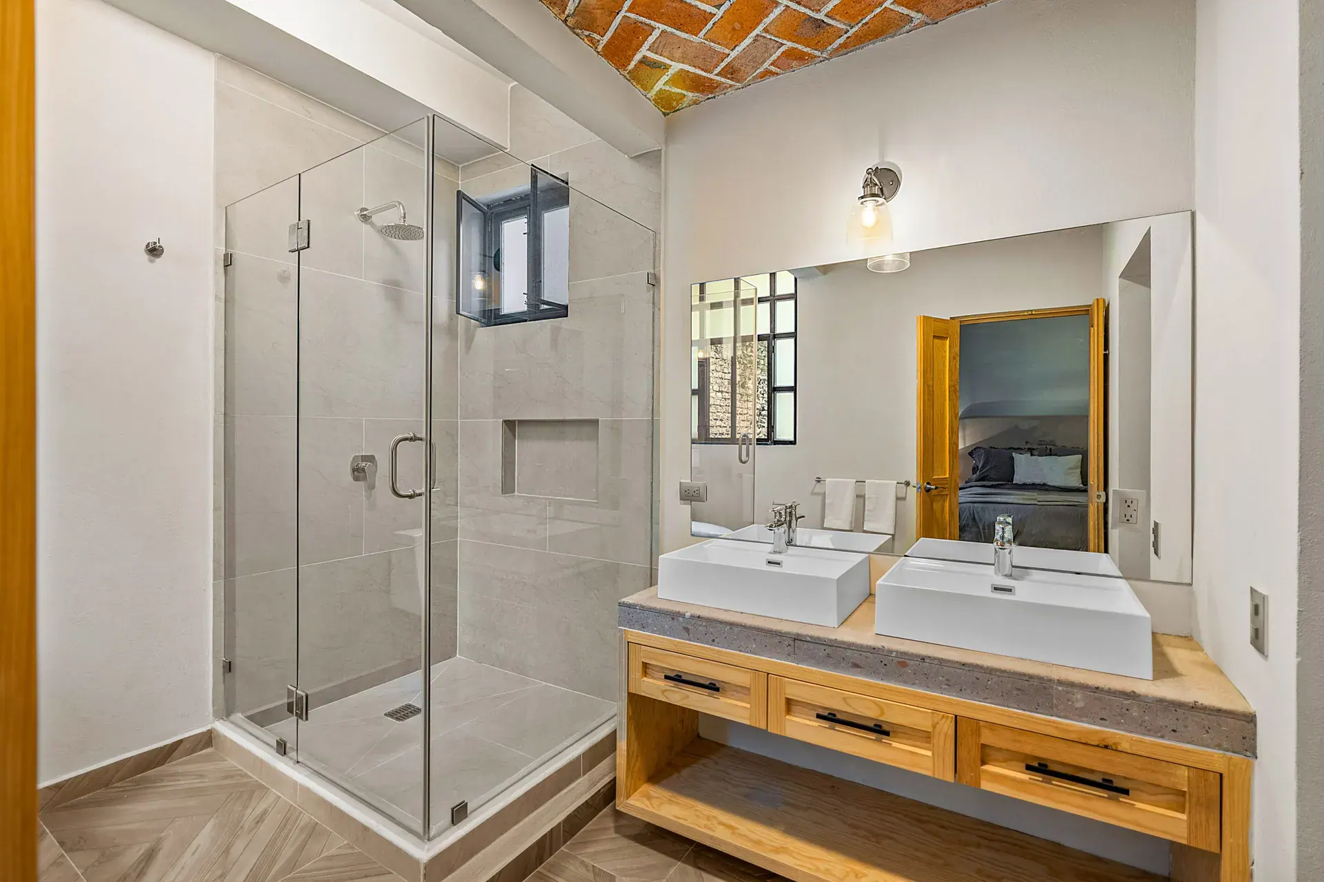 Casa Hidalgo, bathroom with a glass shower, a double wood vanity with two vessel sinks and a brick vaulted ceiling, San Miguel de Allende