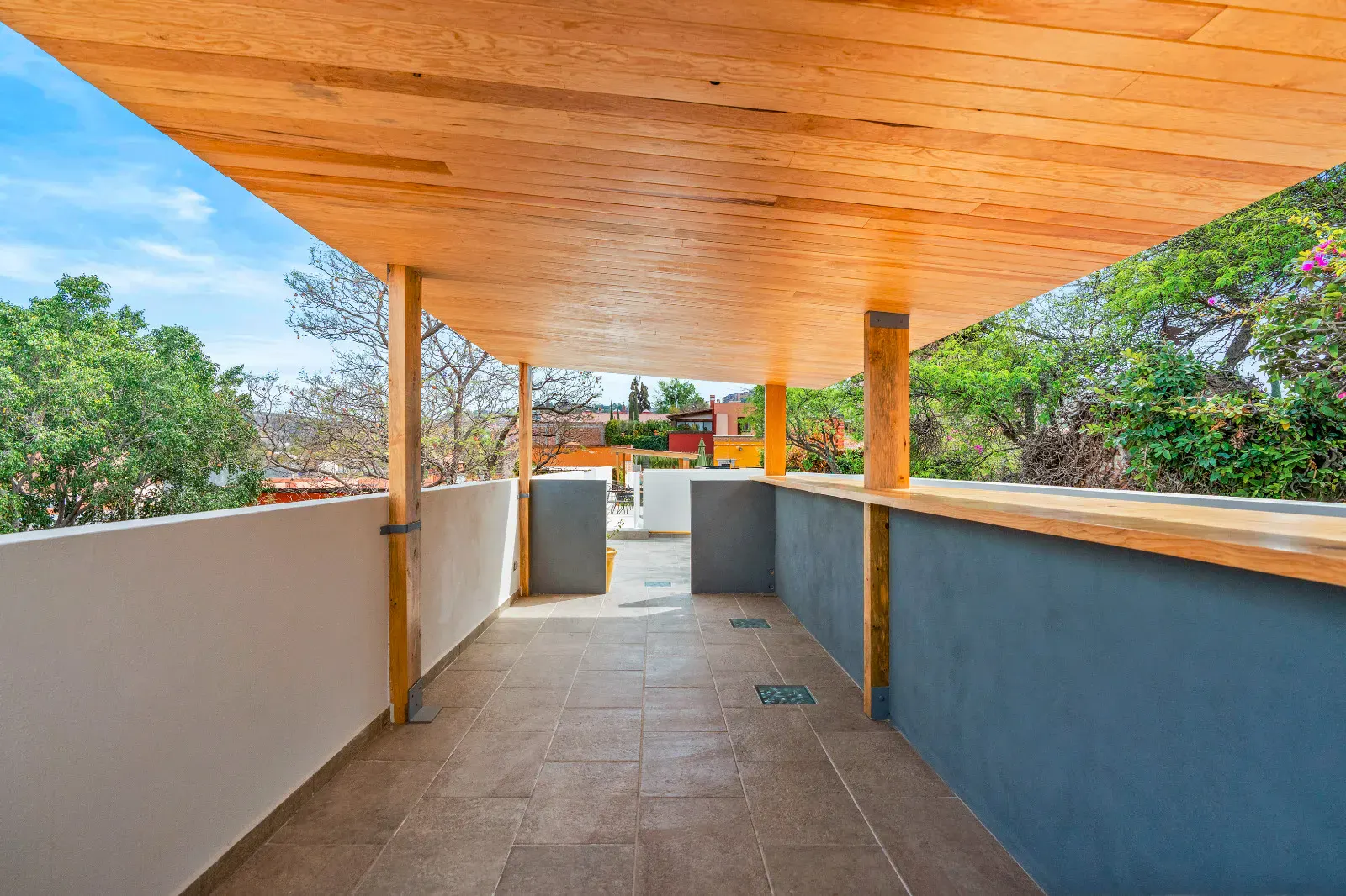 Casa Hidalgo, covered rooftop walkway with a wood slat roof, a tile floor and a view of the treetops, San Miguel de Allende