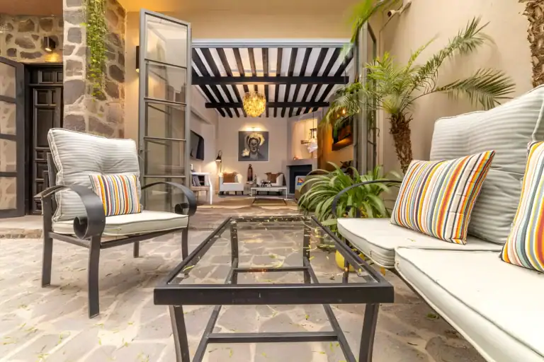 Casa Huerta, courtyard lounge with a striped-cushion sofa, a glass coffee table and the living room visible beyond glass doors, San Miguel de Allende