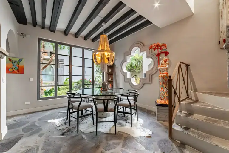 Casa Huerta, dining area with a glass round table, black chairs, a beam ceiling, a shell chandelier and a staircase, San Miguel de Allende