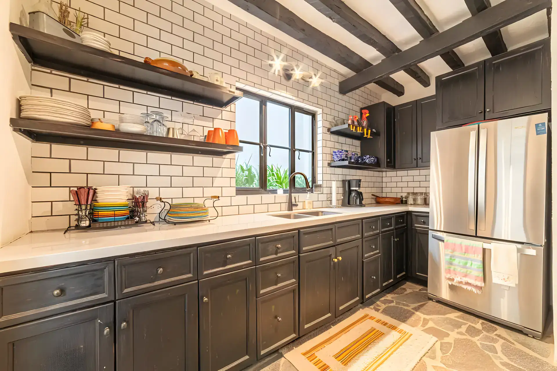 Casa Huerta, kitchen with black cabinets, a white subway tile wall, open shelves and a stainless refrigerator, San Miguel de Allende