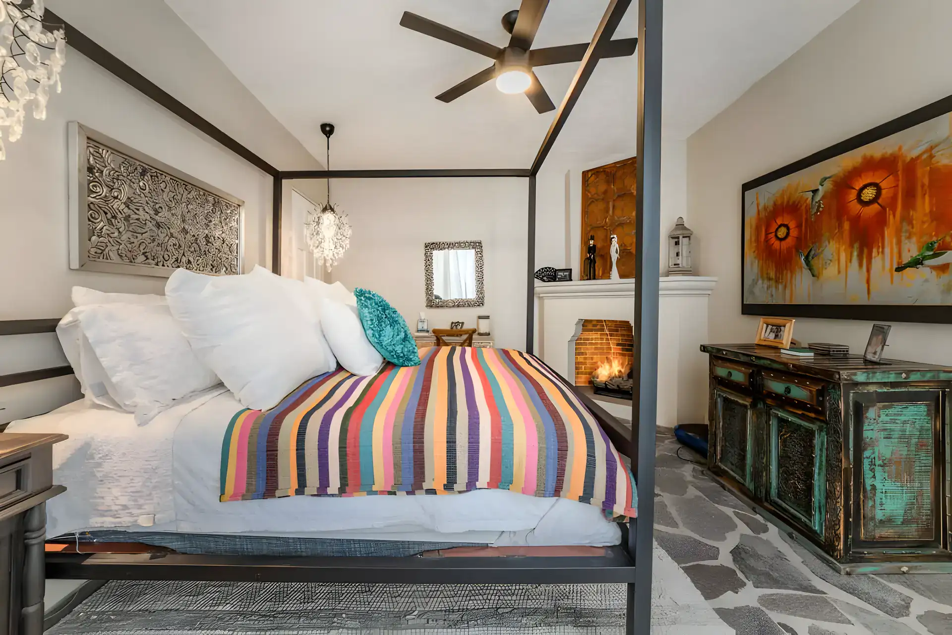 Casa Huerta, bedroom with a black canopy bed, a striped blanket, a fireplace and a painted turquoise chest, San Miguel de Allende