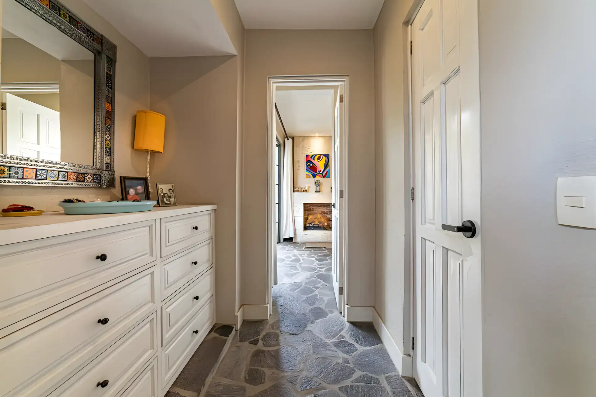 Casa Huerta, hallway with a white dresser, a metal mirror and a view to a fireplace in another room, San Miguel de Allende