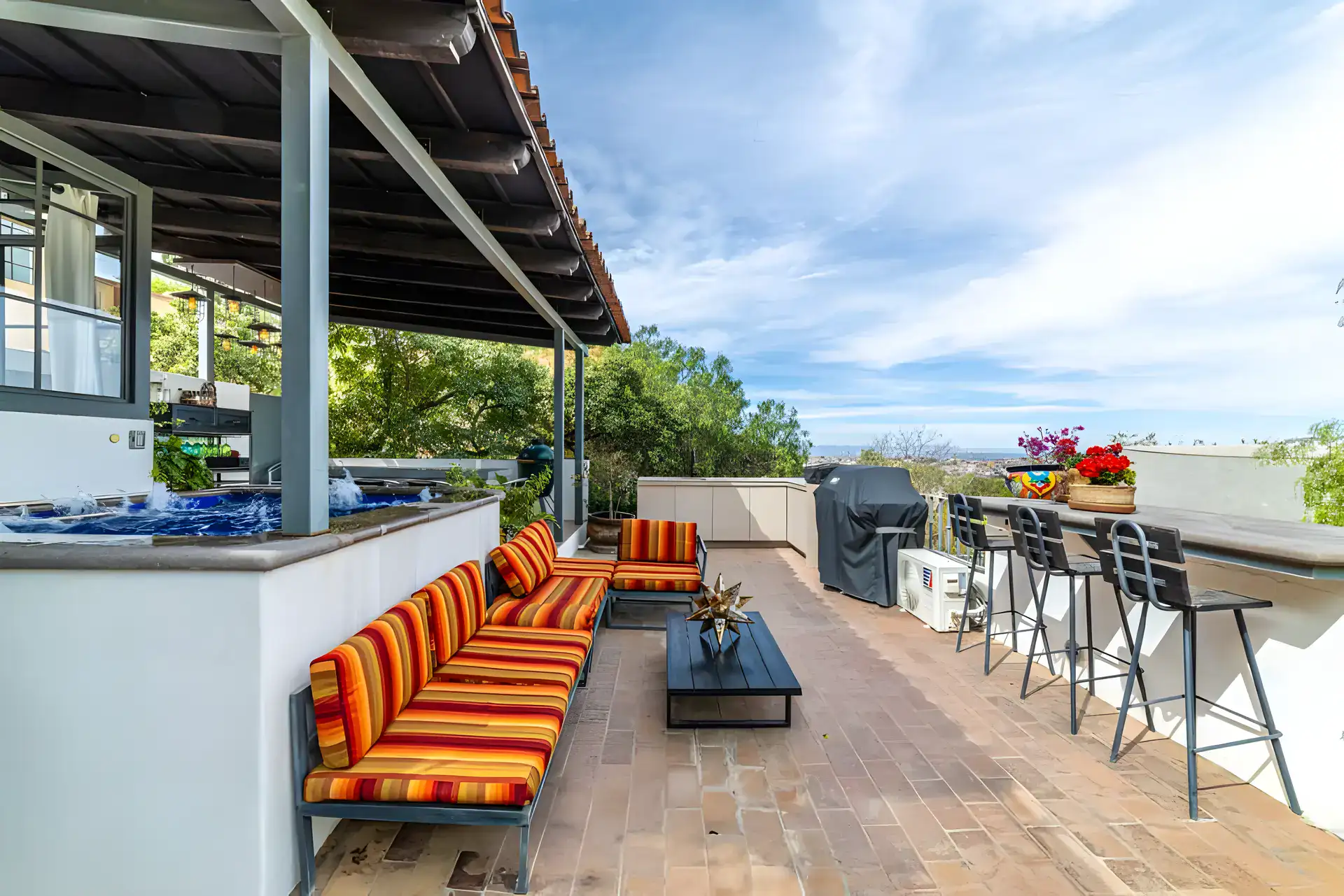 Casa Huerta, rooftop terrace with a spa, striped orange sofas, a barbecue and a bar with stools, San Miguel de Allende