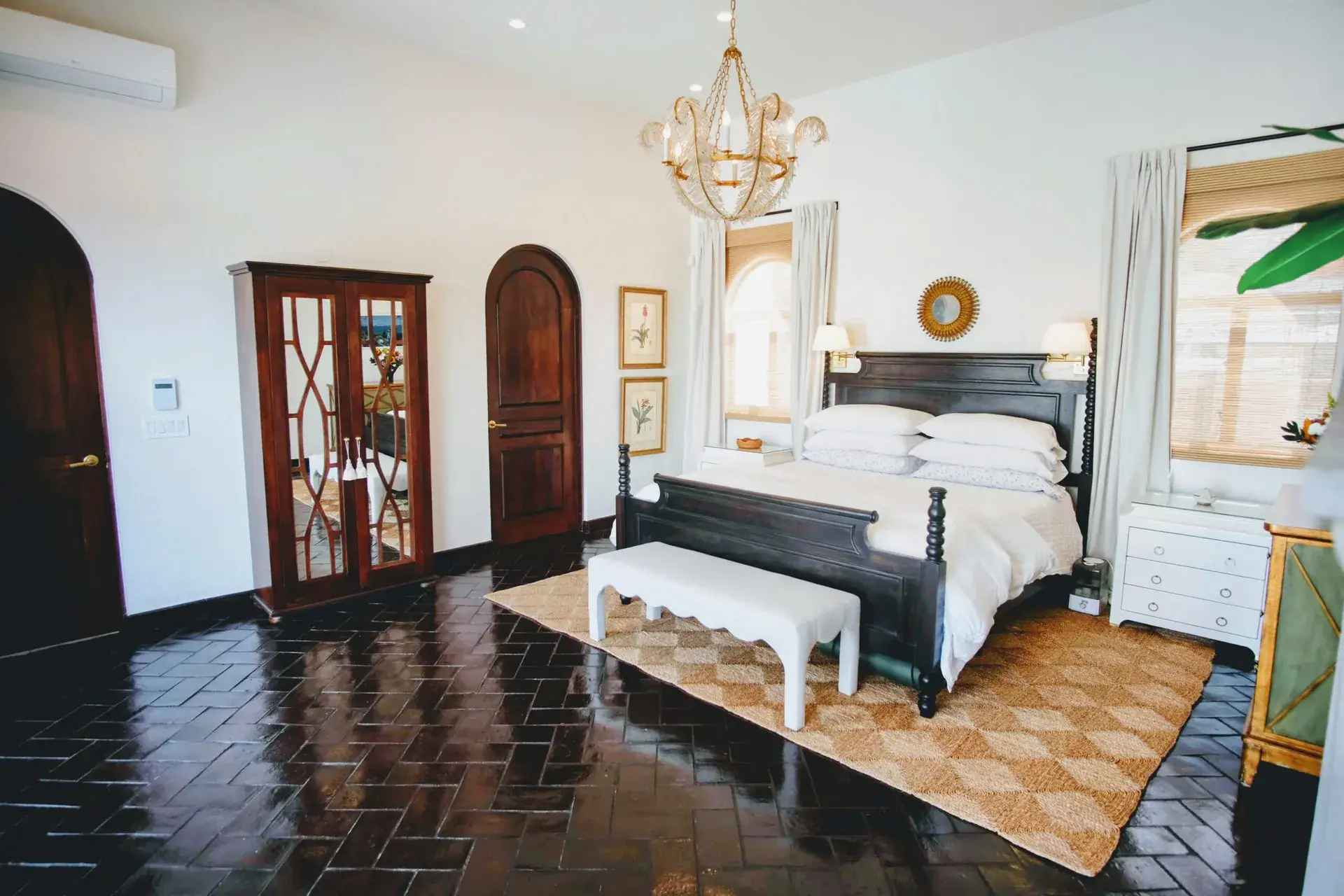 Casa Jacaranda, primary bedroom with a dark four-poster bed, chandelier and arched doors, San Miguel de Allende