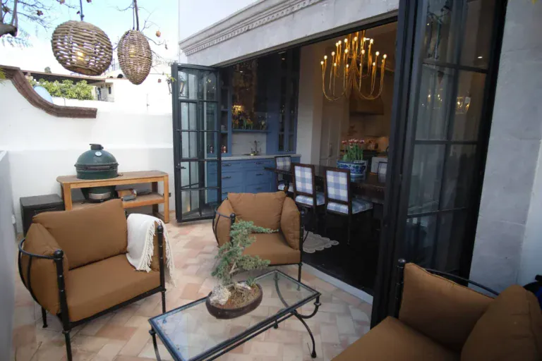 Casa Jacaranda, outdoor lounge with leather chairs beside open black steel doors, San Miguel de Allende
