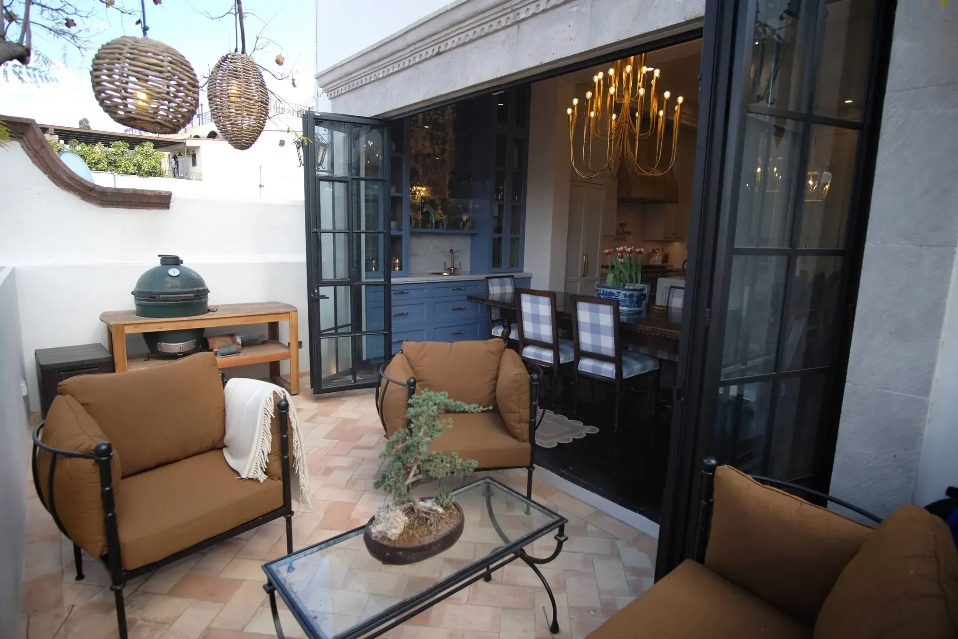 Casa Jacaranda, outdoor lounge with leather chairs beside open black steel doors, San Miguel de Allende