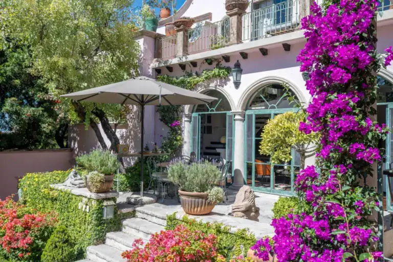 Casa Jardín, garden terrace with an umbrella and purple bougainvillea beside the arched doors, San Miguel de Allende