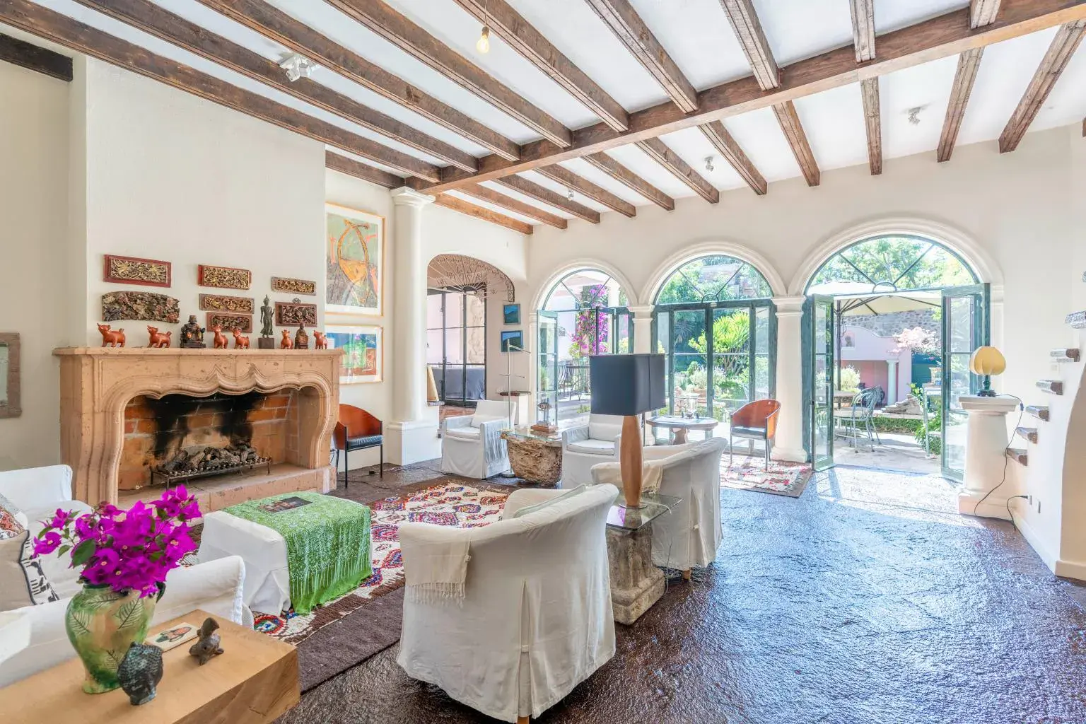 Casa Jardín, living room with a stone fireplace, arched windows and a beamed ceiling, San Miguel de Allende