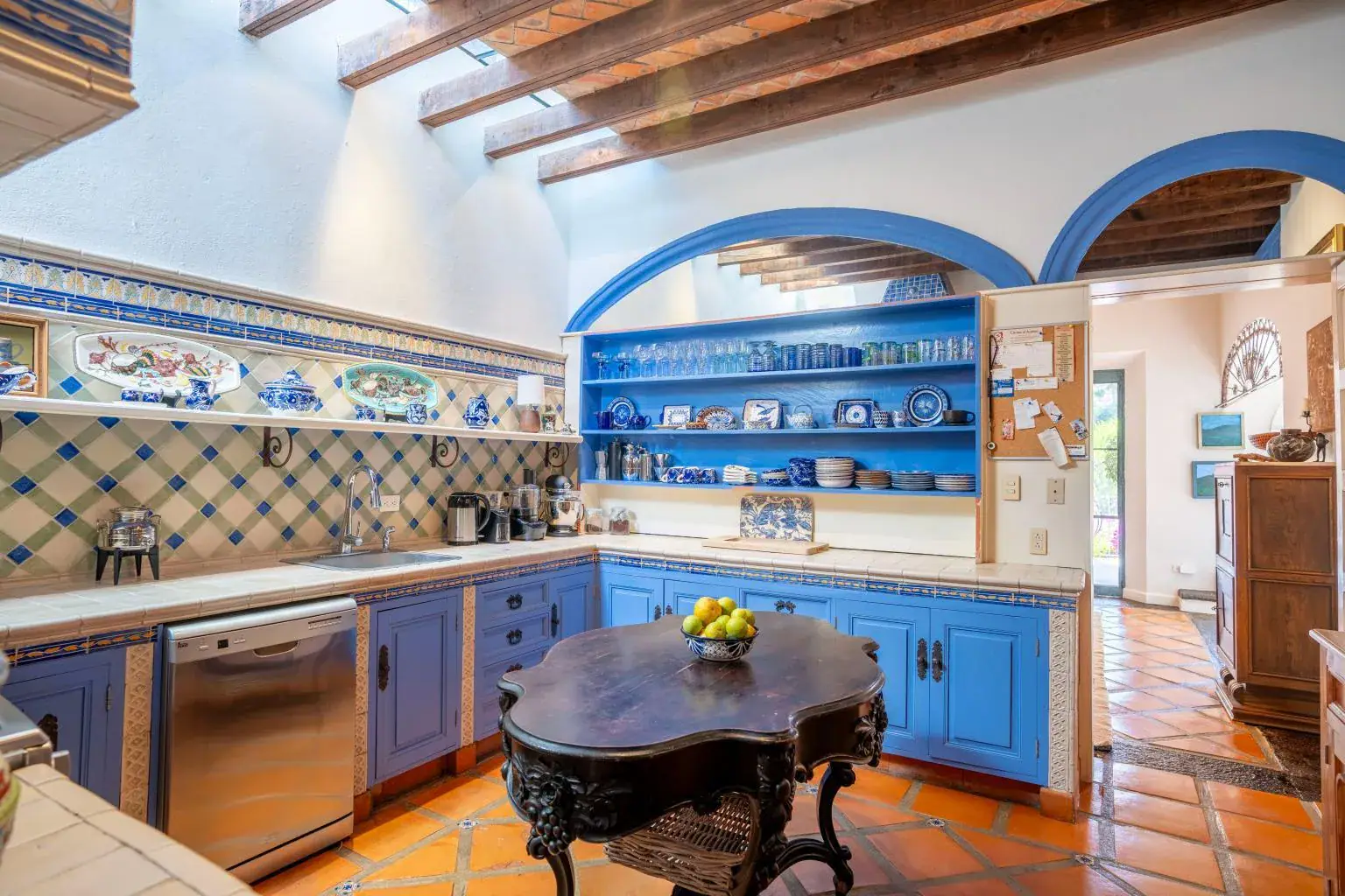 Casa Jardín, kitchen with blue tile arches, open shelves and a carved wood center table, San Miguel de Allende